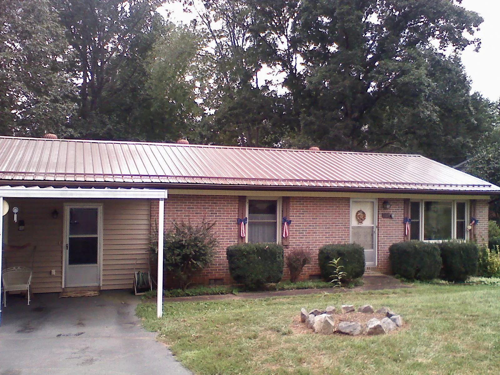 Bronze metal roof and carport on a brick ranch home — Roof Repair work by our crew in Divide